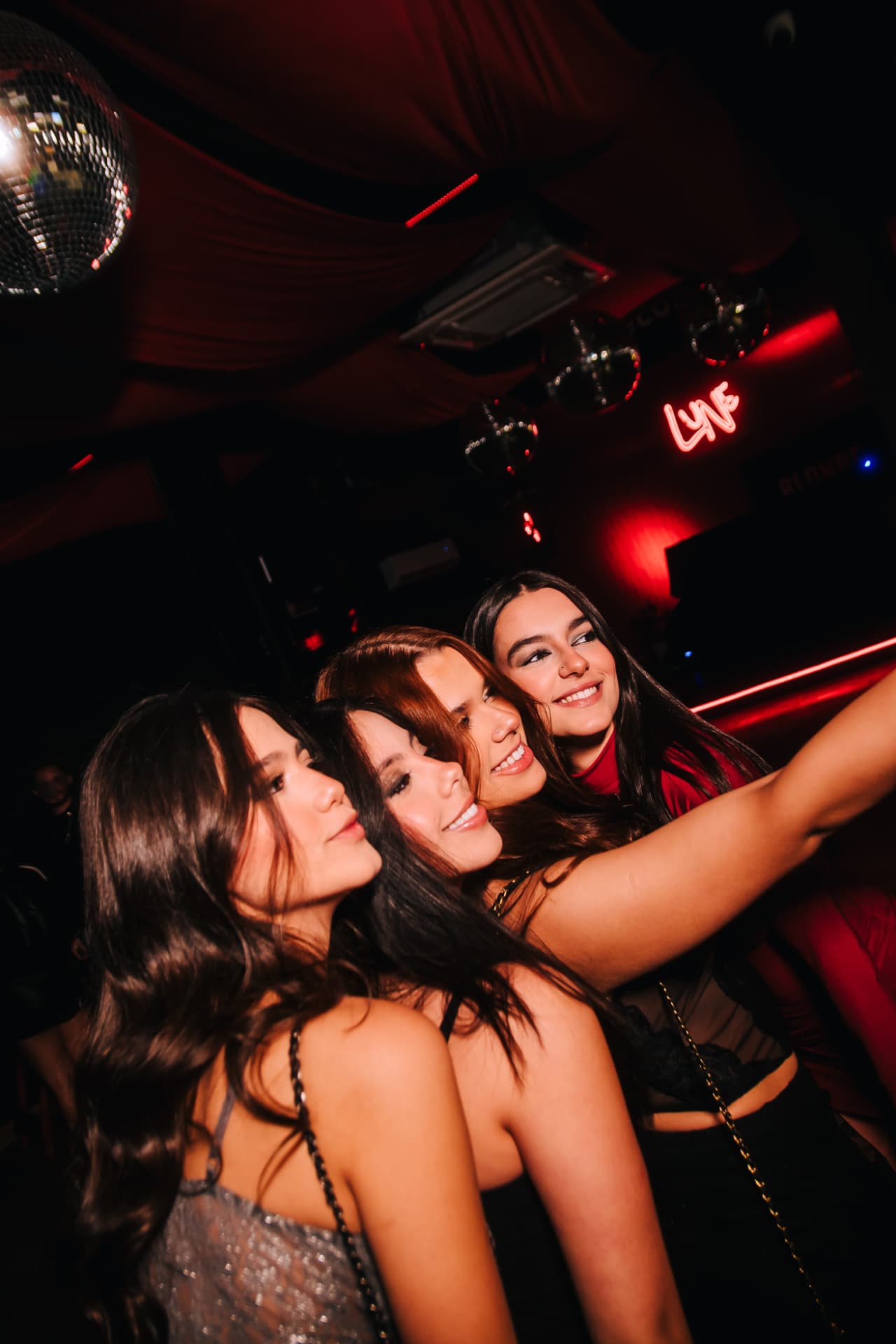 Amigas sob o letreiro neon da Lune